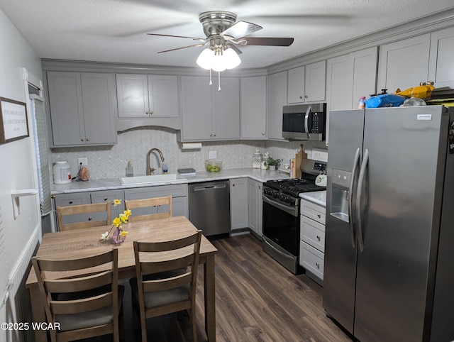 kitchen featuring a sink, a ceiling fan, gray cabinets, light countertops, and appliances with stainless steel finishes