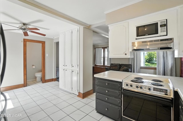 1574 Oakland Pkwy, Lima, OH 45805 - kitchen with white microwave, electric stovetop, white cabinetry, light countertops, and a ceiling fan