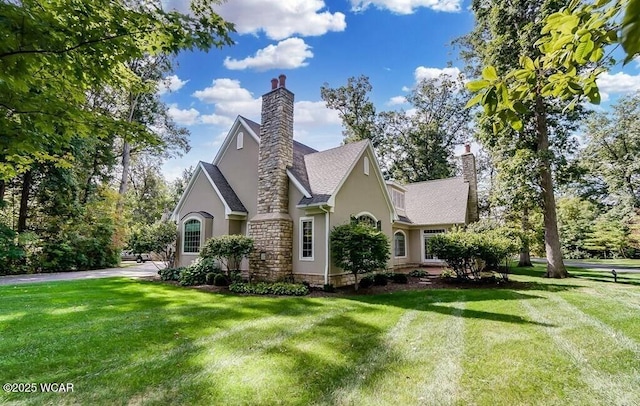 view of side of home with stucco siding, a yard, and a chimney