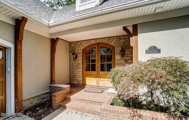doorway to property with covered porch, stone siding, roof with shingles, stucco siding, and french doors