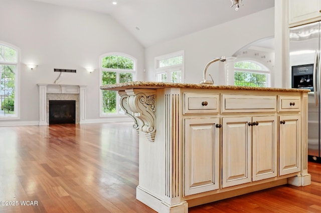 7 Estate Dr, Lima, OH 45805 - kitchen with plenty of natural light, wood finished floors, high vaulted ceiling, a fireplace, and stainless steel fridge with ice dispenser