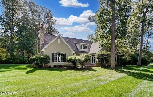 rear view of house featuring stucco siding, a yard, and a chimney