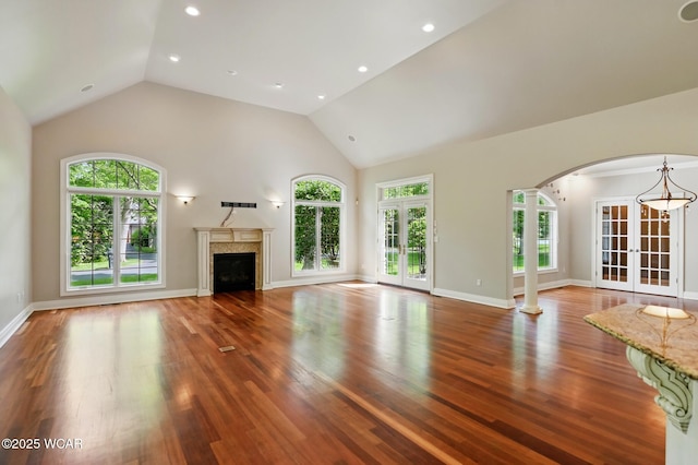 7 Estate Dr, Lima, OH 45805 - unfurnished living room with french doors, arched walkways, wood finished floors, a fireplace, and ornate columns