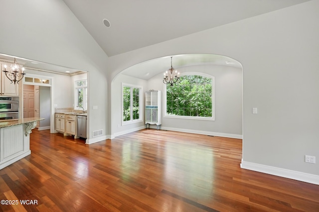 7 Estate Dr, Lima, OH 45805 - unfurnished living room with a chandelier, arched walkways, a sink, wood finished floors, and high vaulted ceiling