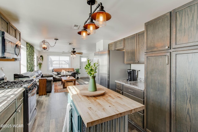 kitchen with a kitchen island, pendant lighting, wood counters, wood-type flooring, and stainless steel appliances