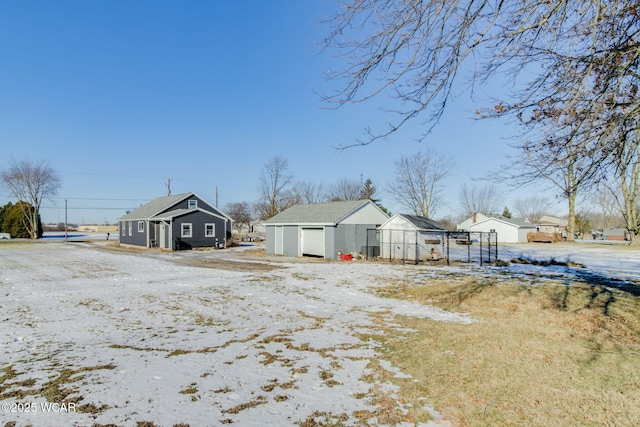 snow covered house featuring a garage and an outdoor structure