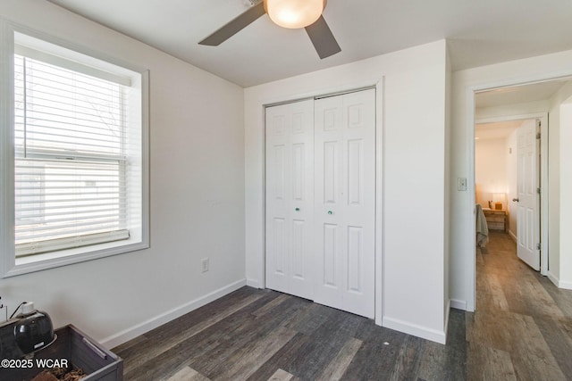 unfurnished bedroom with dark wood-type flooring, ceiling fan, and a closet