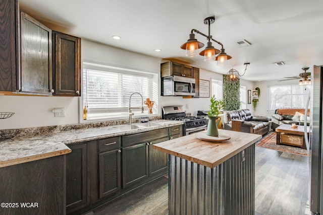 kitchen with sink, dark wood-type flooring, wooden counters, hanging light fixtures, and stainless steel appliances