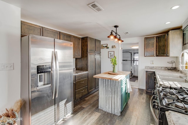 kitchen with butcher block countertops, sink, a center island, gas stove, and stainless steel refrigerator with ice dispenser