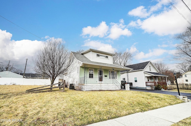 view of front of house with central air condition unit, a porch, board and batten siding, a front yard, and fence