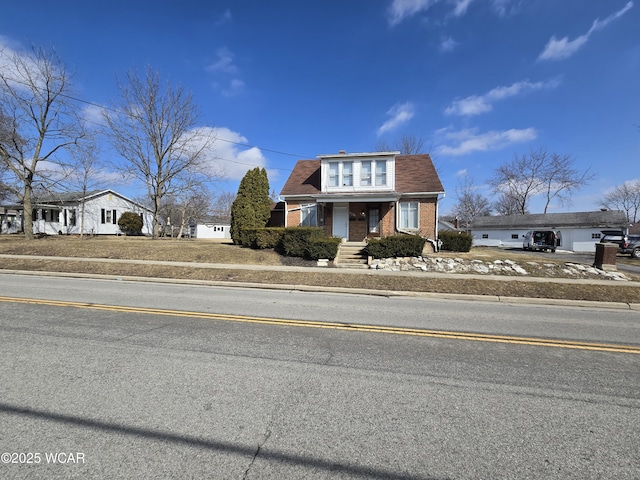 view of front of home with covered porch, concrete driveway, brick siding, and a shingled roof