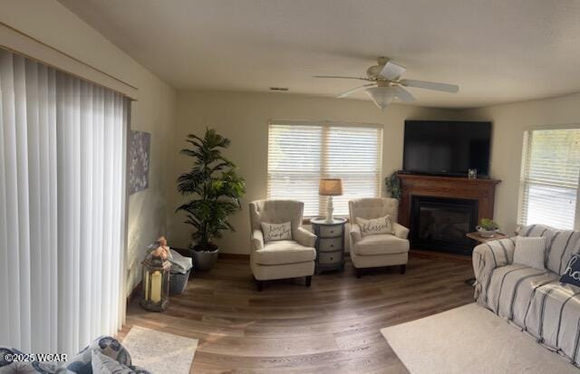 living room with a ceiling fan, dark wood-style flooring, and a glass covered fireplace