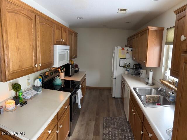 kitchen with brown cabinets, white appliances, light countertops, and a sink