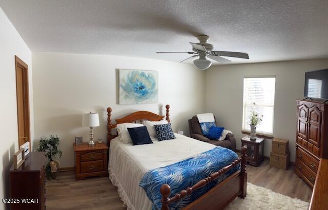 bedroom with light wood-type flooring, a ceiling fan, and a textured ceiling