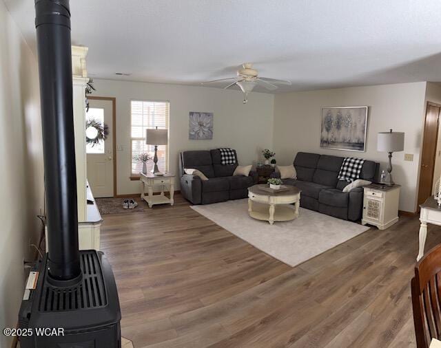 living room with a wood stove, ceiling fan, and dark wood-style flooring