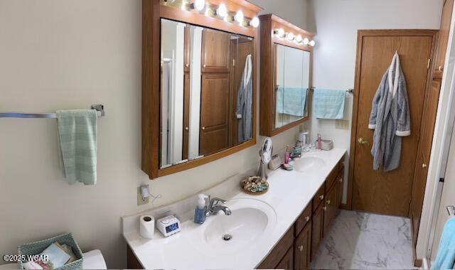 full bath featuring double vanity, marble finish floor, and a sink