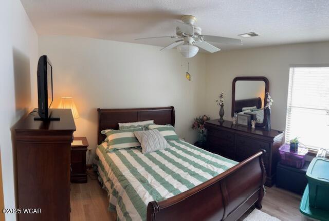 bedroom featuring visible vents, ceiling fan, and light wood-style flooring