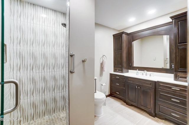 bathroom featuring vanity, tiled shower, and toilet