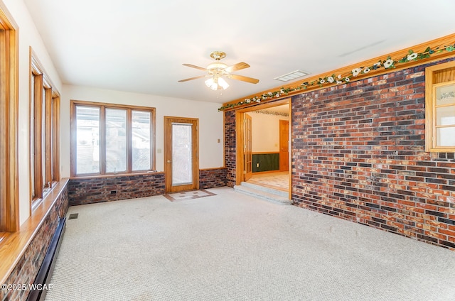 unfurnished living room with brick wall, light colored carpet, and ceiling fan