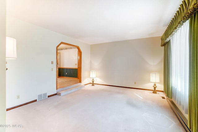 empty room featuring a baseboard radiator and light colored carpet