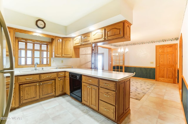 kitchen featuring decorative light fixtures, black dishwasher, sink, stainless steel fridge, and kitchen peninsula