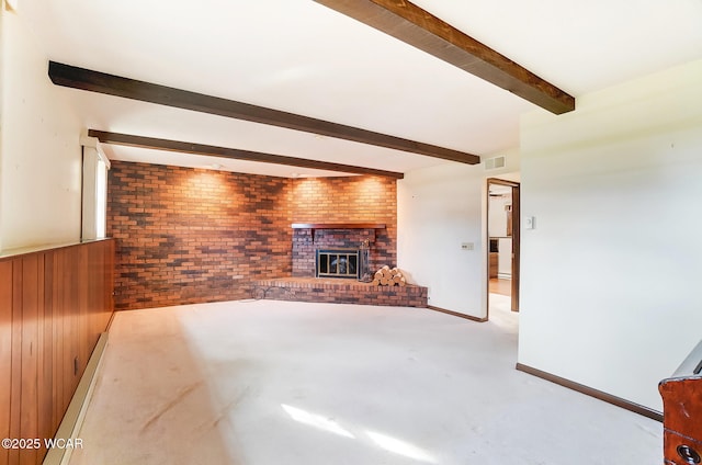 unfurnished living room with beamed ceiling, brick wall, wood walls, and a brick fireplace