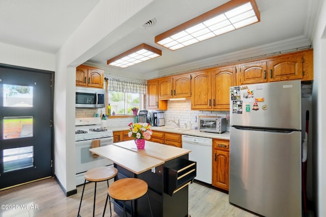 718 Wildwood Ave, Lima, OH 45807 - kitchen featuring appliances with stainless steel finishes, a sink, light countertops, decorative backsplash, and light wood finished floors