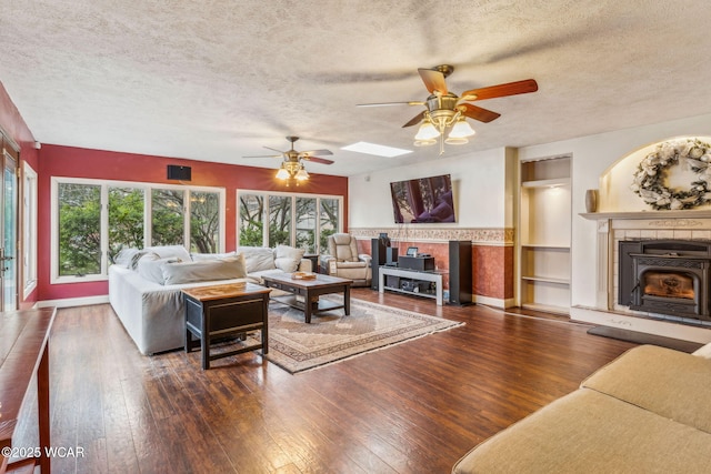 living room with dark wood-type flooring, ceiling fan, and a textured ceiling