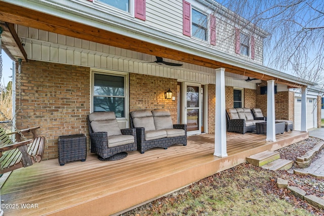 wooden terrace with an outdoor living space, a garage, ceiling fan, and a porch