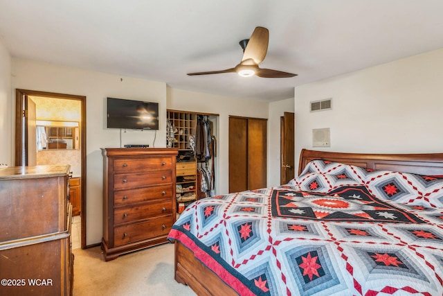 bedroom with two closets, light colored carpet, and ceiling fan