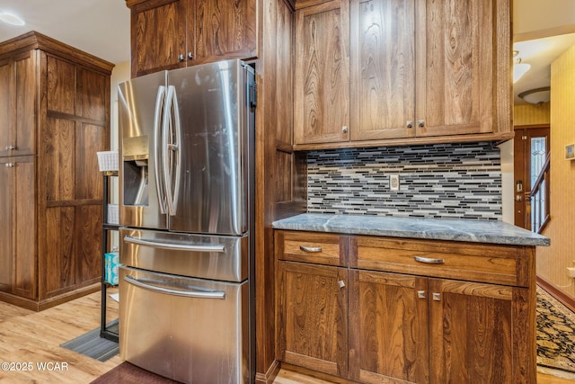 kitchen featuring stainless steel fridge, light stone countertops, decorative backsplash, and light hardwood / wood-style flooring