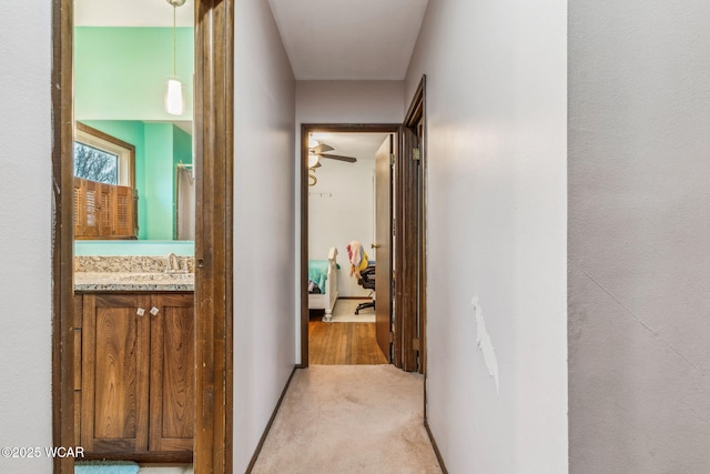 hallway with sink and light colored carpet