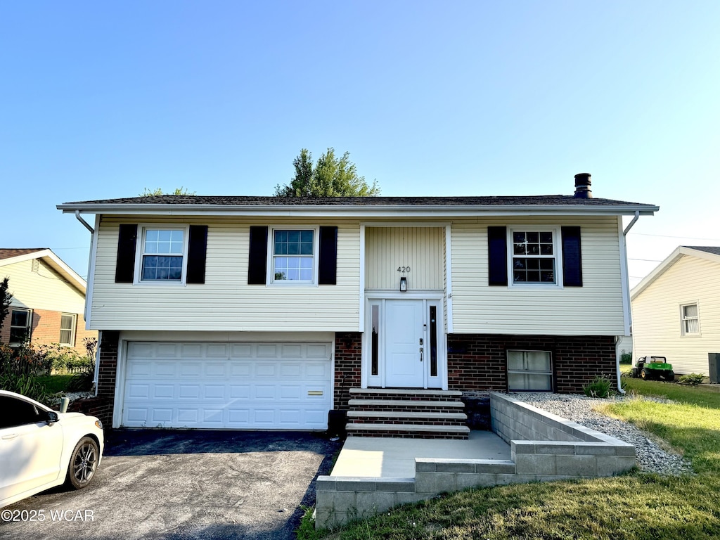 420 Sheffield Dr, Findlay, OH 45840 - raised ranch with asphalt driveway, an attached garage, brick siding, and entry steps
