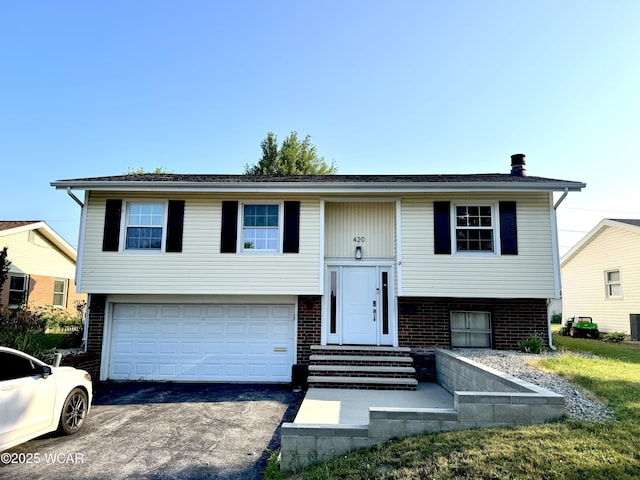 420 Sheffield Dr, Findlay, OH 45840 - raised ranch with asphalt driveway, an attached garage, brick siding, and entry steps