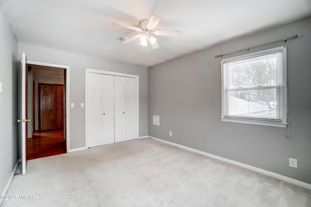 unfurnished bedroom with light carpet, ceiling fan, baseboards, and a closet