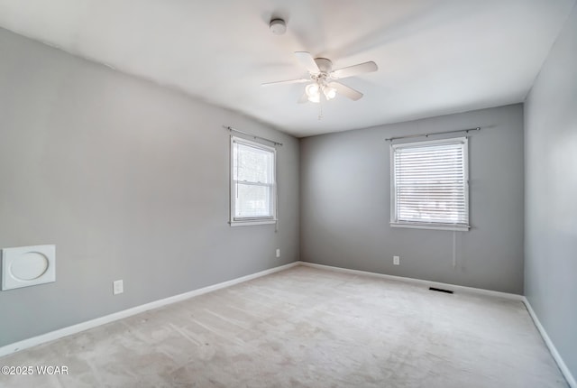 unfurnished room with ceiling fan, light carpet, visible vents, and baseboards