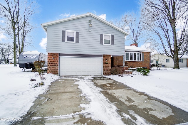 tri-level home with driveway, an attached garage, and brick siding