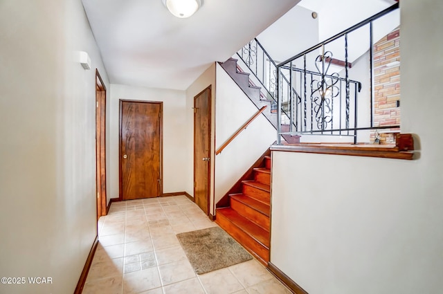 foyer with stairway, baseboards, and light tile patterned floors