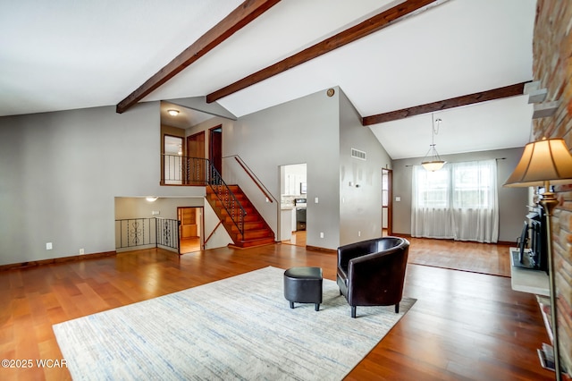 living room featuring baseboards, visible vents, stairway, wood finished floors, and beam ceiling