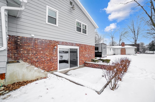 snow covered back of property with brick siding