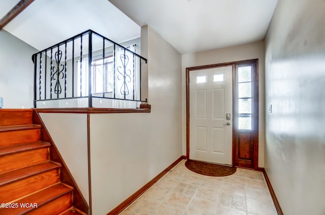 foyer featuring baseboards and stairs