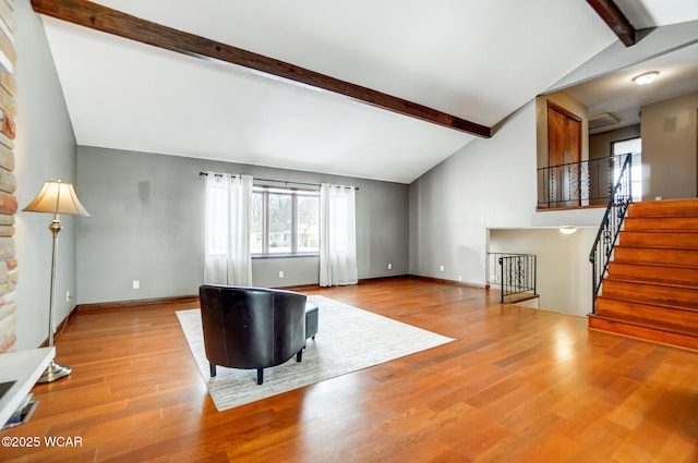 unfurnished living room featuring light wood-style floors, beamed ceiling, stairway, and baseboards