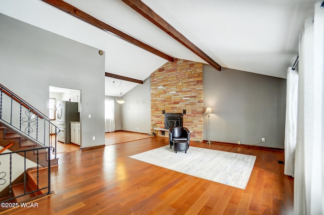 living area with wood finished floors, baseboards, stairs, beamed ceiling, and a wood stove