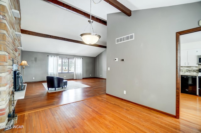 unfurnished living room featuring light wood finished floors, a fireplace, visible vents, and beam ceiling