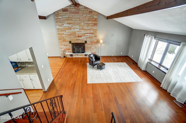 living room with light wood-type flooring, lofted ceiling with beams, and baseboards