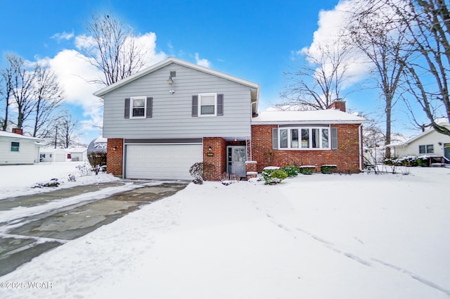 split level home with an attached garage, a chimney, and brick siding