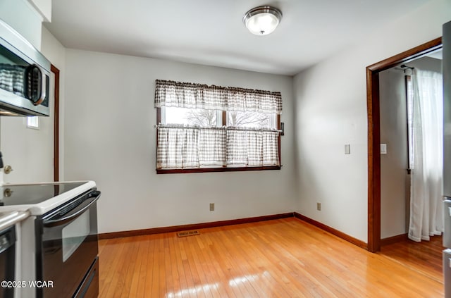 kitchen featuring visible vents, baseboards, electric stove, stainless steel microwave, and light wood-style floors