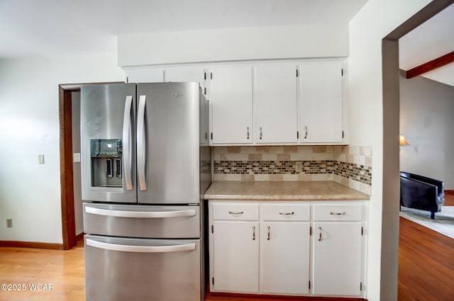 kitchen featuring light wood-style floors, white cabinets, light countertops, stainless steel fridge with ice dispenser, and tasteful backsplash