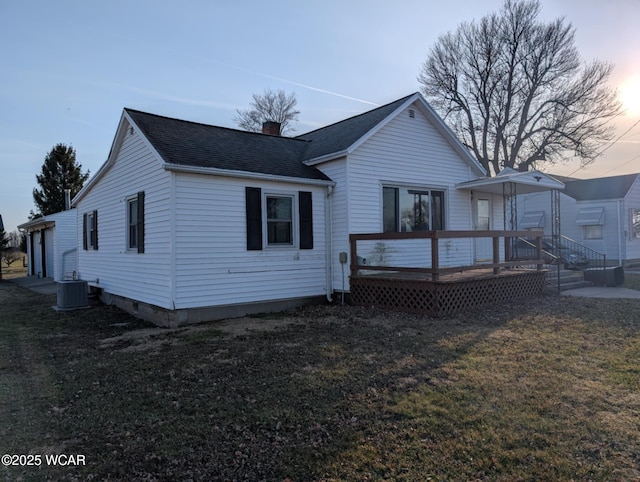 back of house featuring a wooden deck, roof with shingles, central AC unit, a lawn, and a chimney