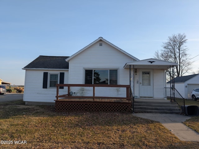 view of front of house featuring a wooden deck, roof with shingles, and a front lawn